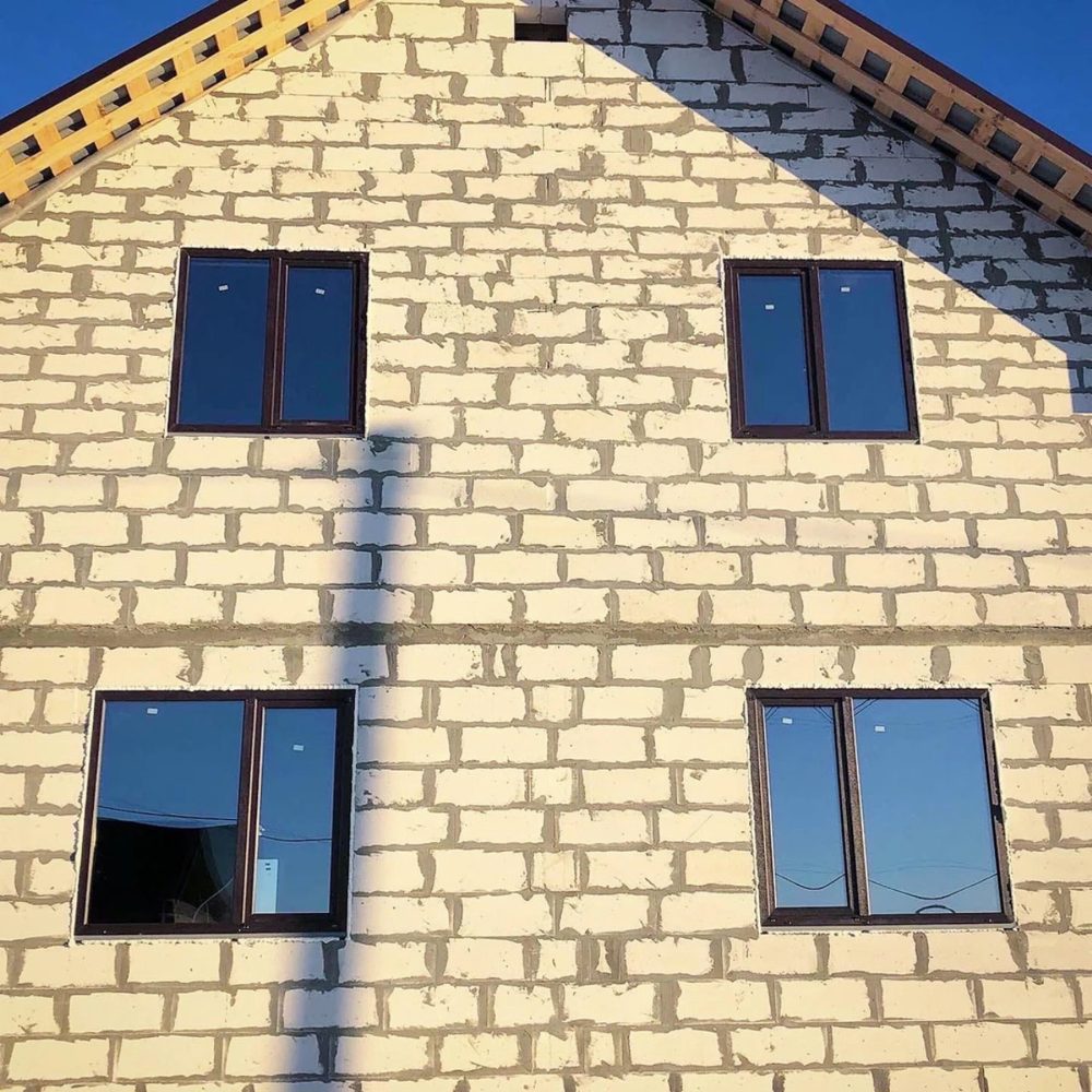 Фронтон дома из газоблока с четырьмя окнами в тёмной ламинации